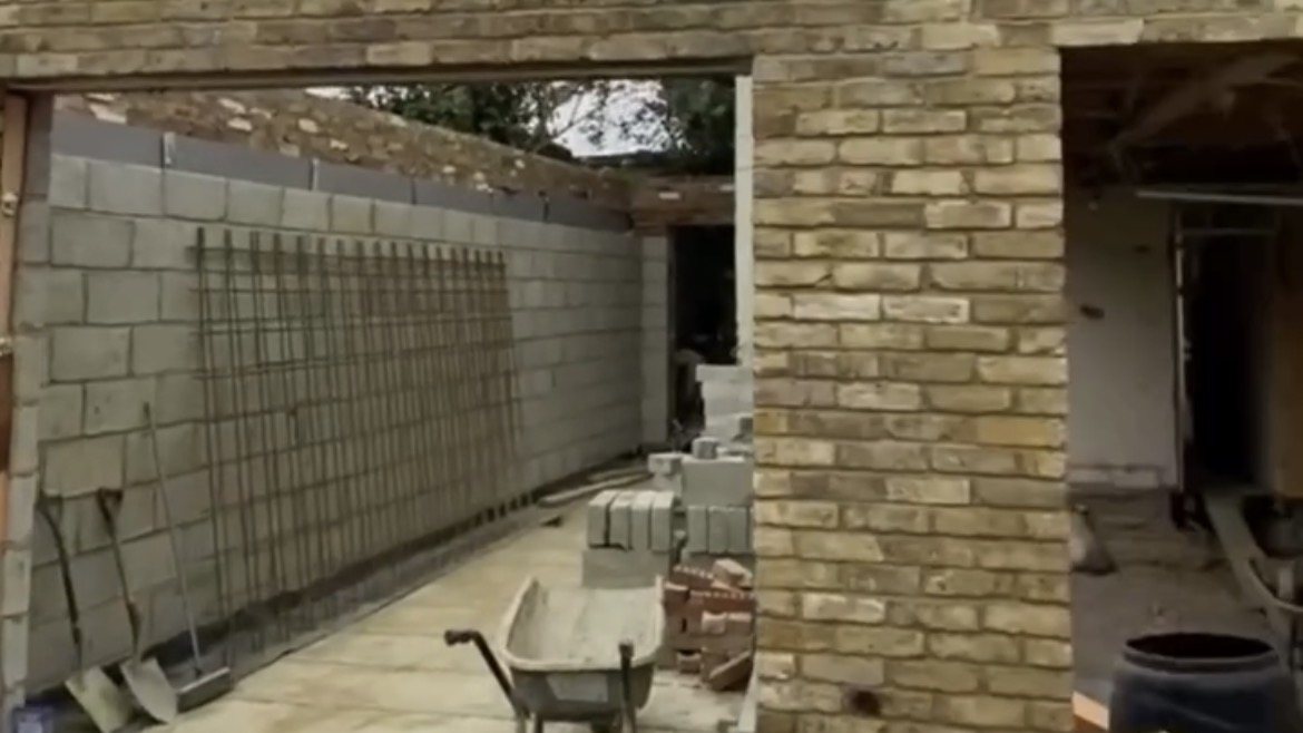A part-built rear extension: blockwork, brick opening and a wheelbarrow.